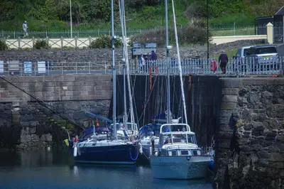 three boats docked in the water next to a wall at Cedar Lodge in Portpatrick