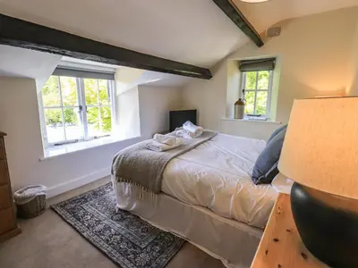 a bedroom with a bed and two windows at St Giles in Ambleside