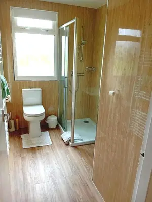 a bathroom with a toilet and a glass shower at Glen Dhoo Country Cottages - Meadowview Bungalow in Onchan