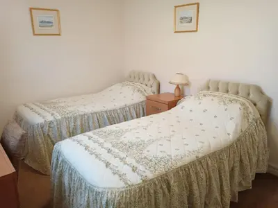 two twin beds in a room with a dresser and a lamp at Glen Dhoo Country Cottages - Meadowview Bungalow in Onchan