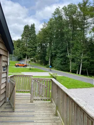 a wooden walkway leading to a yard with a car at Squirrel Lodge 40 with Hot Tub in Newton Stewart