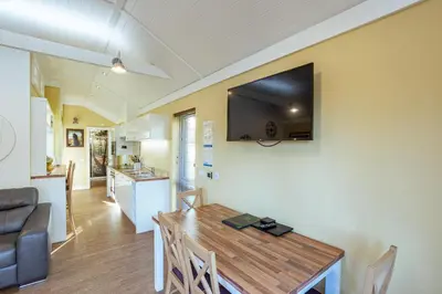 a living room with a dining room table with a television on the wall at Squirrel Lodge 41 with Hot Tub in Newton Stewart