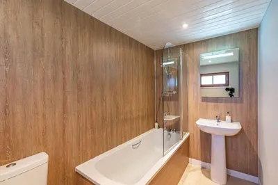 a bathroom with a sink and a bath tub and a toilet at Lady Galloway 27 with Hot Tub in Newton Stewart