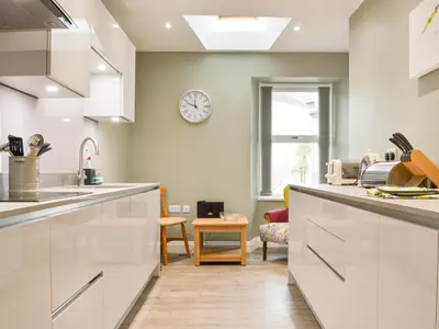 a kitchen with white cabinets and a clock on the wall at 1 Harney Peak in Portinscale