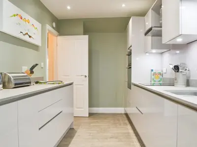 a kitchen with white cabinets and a sink at 1 Harney Peak in Portinscale