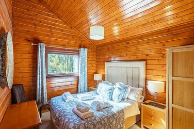 a bedroom with a bed in a wooden cabin at Lady Galloway 28 with Hot Tub in Newton Stewart