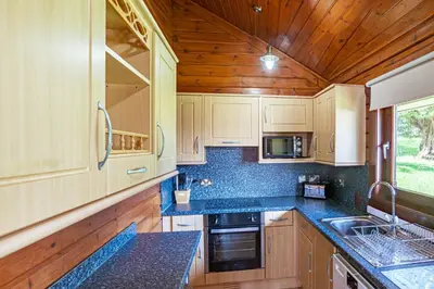 a kitchen with wooden cabinets and blue counter tops at Lady Galloway 28 with Hot Tub in Newton Stewart
