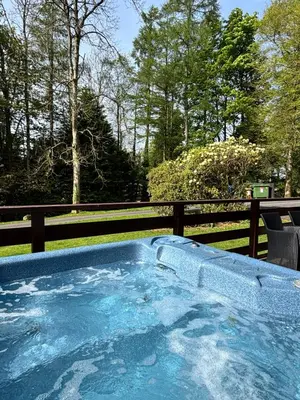 a hot tub in a yard with a fence and trees at Lady Galloway 29 with Hot Tub in Newton Stewart
