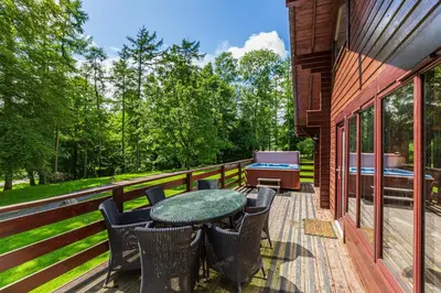 a deck with a table and chairs and a grill at Lady Galloway 30 with Hot Tub in Newton Stewart