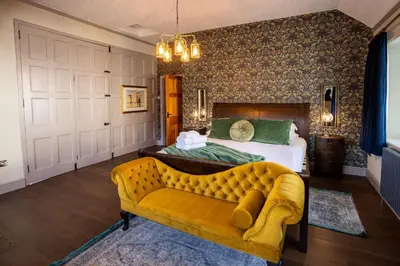 a bedroom with a bed and a yellow couch at Greta Howe in Keswick