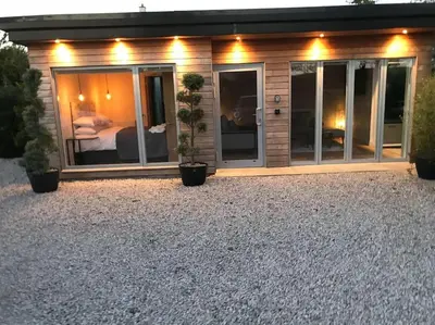 a house with glass doors and potted plants in front of it at Amazing Cottage & detached Annex sleeps 8, Extra Deep Hot tub, Super Fast wifi, New for 2024 is the addition of Wood Fired Sauna in Castle Douglas