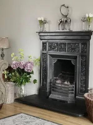 a black fireplace in a living room with flowers at Amazing Cottage & detached Annex sleeps 8, Extra Deep Hot tub, Super Fast wifi, New for 2024 is the addition of Wood Fired Sauna in Castle Douglas
