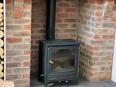 a black stove in a brick wall at Cosy country cottage in rural location in Moffat