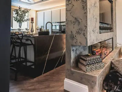 a living room with a fireplace and a kitchen at Whisk Away Cottage in Penrith