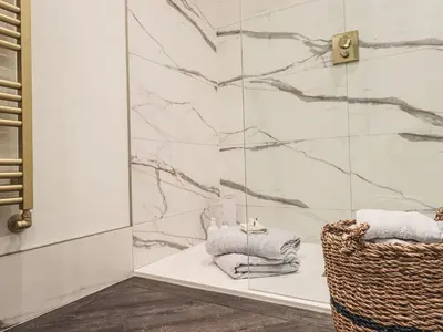 a bathroom with a shower with towels and a basket at Whisk Away Cottage in Penrith