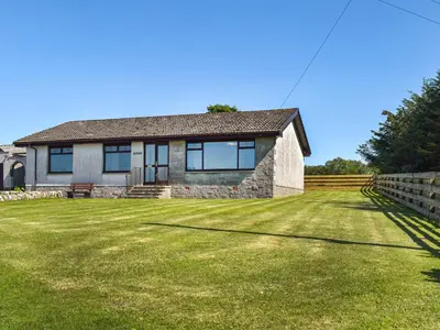 a house with a grassy yard in front of it at Lowesmuir Cottage in Cumnock