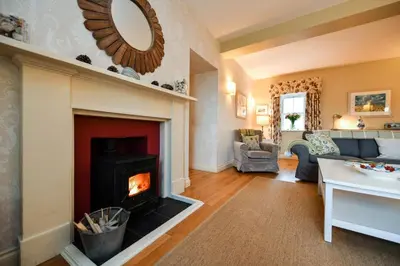 a living room with a fireplace and a couch at High Clachan Farmhouse in Stranraer