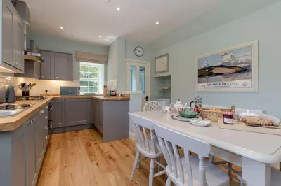 a kitchen with gray cabinets and a large white island at Home Farm Cottage in Stranraer