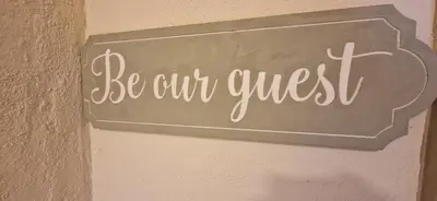 a sign that says be our guest on a wall at Mains Street Retreat in Lockerbie