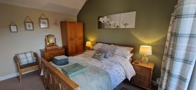 a bedroom with a bed and a dresser and a mirror at Mains Street Retreat in Lockerbie