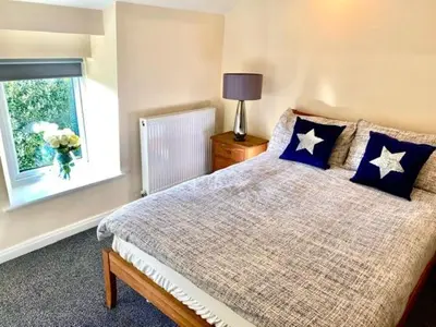 a bedroom with a bed with blue pillows and a window at Mountain Dream Cottage in Ramsey