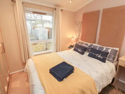 a bedroom with a bed with blue pillows and a window at Rosie's Zen Den in Carlisle