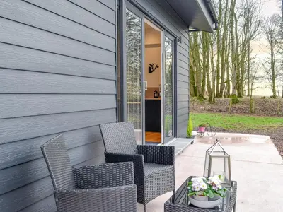 a patio with two chairs and a table at Lime Tree Lodge in Castle Douglas