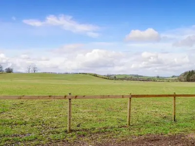 a wooden fence in the middle of a field at Lime Tree Lodge in Castle Douglas
