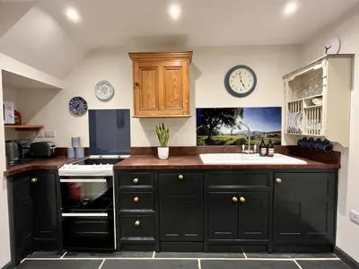 a kitchen with black cabinets and a sink at Stylish & cosy barn minutes from the Lake District in Penrith
