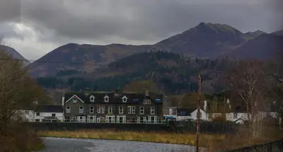 a large building with mountains in the background at Spacious 1st Floor Apartment in Keswick