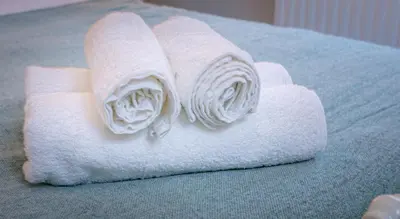 a roll of white towels sitting on a bed at Spacious Ground Floor Apartment in Keswick