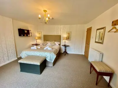 a bedroom with a bed and two benches in it at Elegant & spacious farmhouse with wonderful views in Penrith