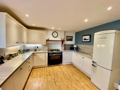 a kitchen with white cabinets and a clock on the wall at Elegant & spacious farmhouse with wonderful views in Penrith