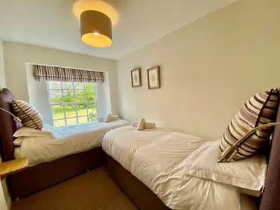 two twin beds in a room with a window at Elegant & spacious farmhouse with wonderful views in Penrith