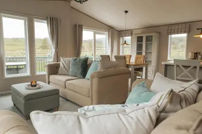 a living room with two couches and a dining room at Snittlegarth Farm Lodges in Wigton
