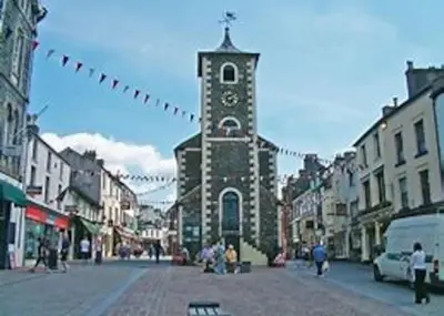 a building with a clock tower in the middle of a street at Pinfold Cottage on the edge of lake district in Bothel