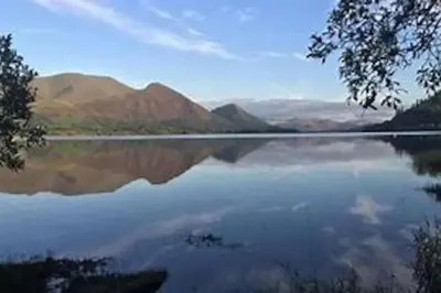 a view of a lake with mountains in the background at Pinfold Cottage on the edge of lake district in Bothel