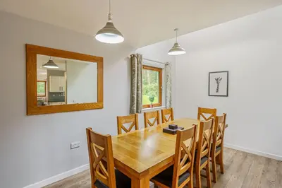 a dining room with a wooden table and chairs and a mirror at Lord Galloway 32 with Hot Tub in Newton Stewart