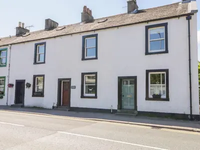 a white house with a green door on a street at The Old Betting Shop in Keswick
