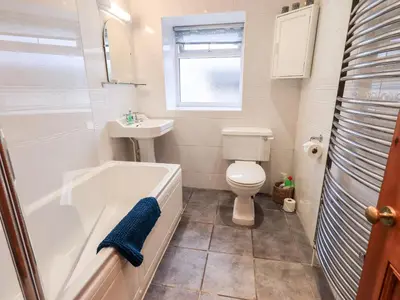 a bathroom with a tub and a toilet and a sink at The Old Betting Shop in Keswick