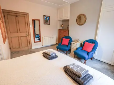 a bedroom with two blue chairs and a bed at The Old Betting Shop in Keswick