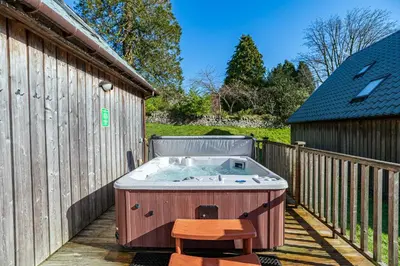 a hot tub on a deck with a wooden fence at Lord Galloway 34 with Hot Tub in Newton Stewart