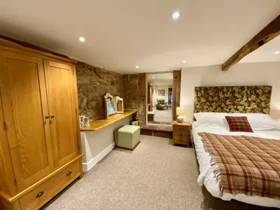 a bedroom with a large bed and a bathroom at Stunning barn minutes from the Lake District in Penrith