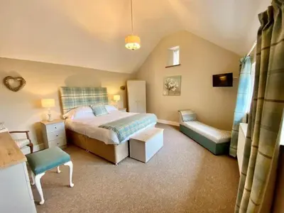 a small bedroom with a bed and a chair at Stunning barn minutes from the Lake District in Penrith