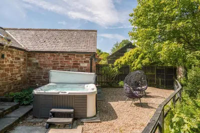 a backyard with a hot tub and a chair at Beckside Cottage, near Carlisle romantic cottage with hot tub in Longtown