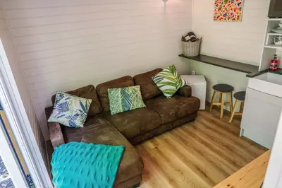 a living room with a brown couch with pillows at Reflections, Netherby, a micro cabin with hot tub in a rural setting in Longtown