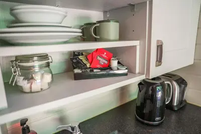 a kitchen cabinet with plates and dishes in it at Reflections, Netherby, a micro cabin with hot tub in a rural setting in Longtown