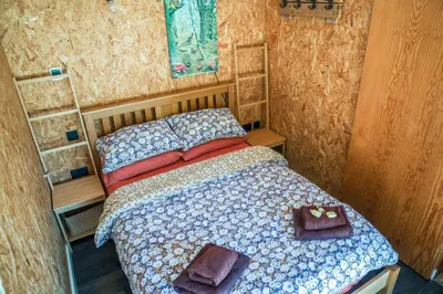 a small bedroom with a bed and two towels at The Chard, Netherby, a micro cabin in a rural setting with a hot tub in Longtown