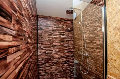 a bathroom with a walk in shower next to a brick wall at The Chard, Netherby, a micro cabin in a rural setting with a hot tub in Longtown