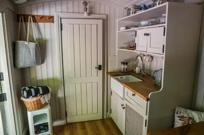 a kitchen with a white door and a sink at The Snug, Netherby, cute shepherds hut with hot tub in a rural location in Longtown